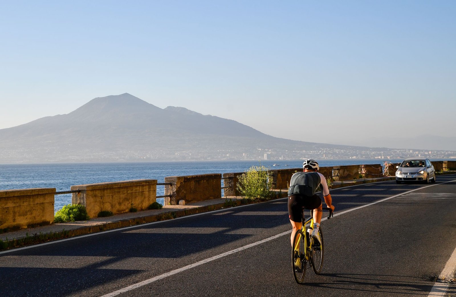 cyclist on coastal road with mount vesuvius view