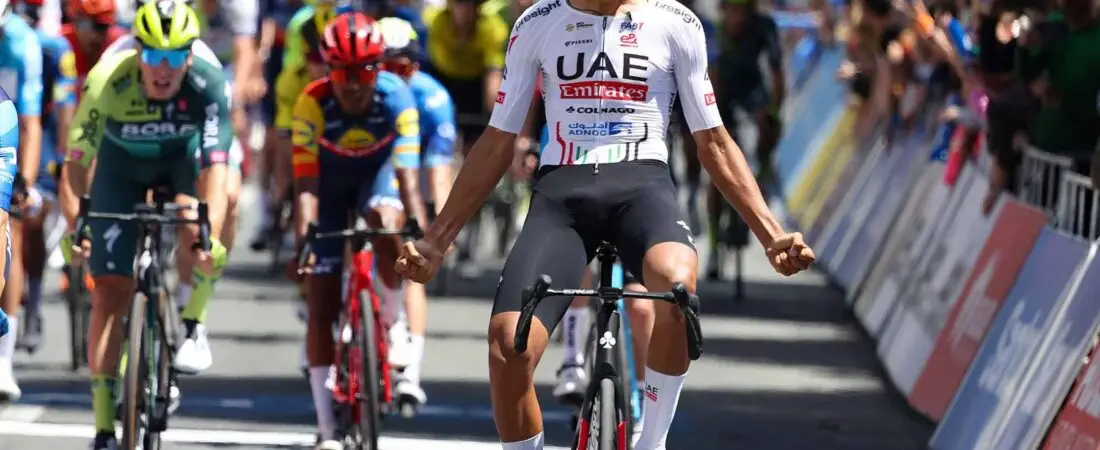 Isaac Del Toro celebrating on the Tour de France podium in the white jersey.