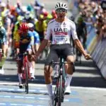 Isaac Del Toro celebrating on the Tour de France podium in the white jersey.