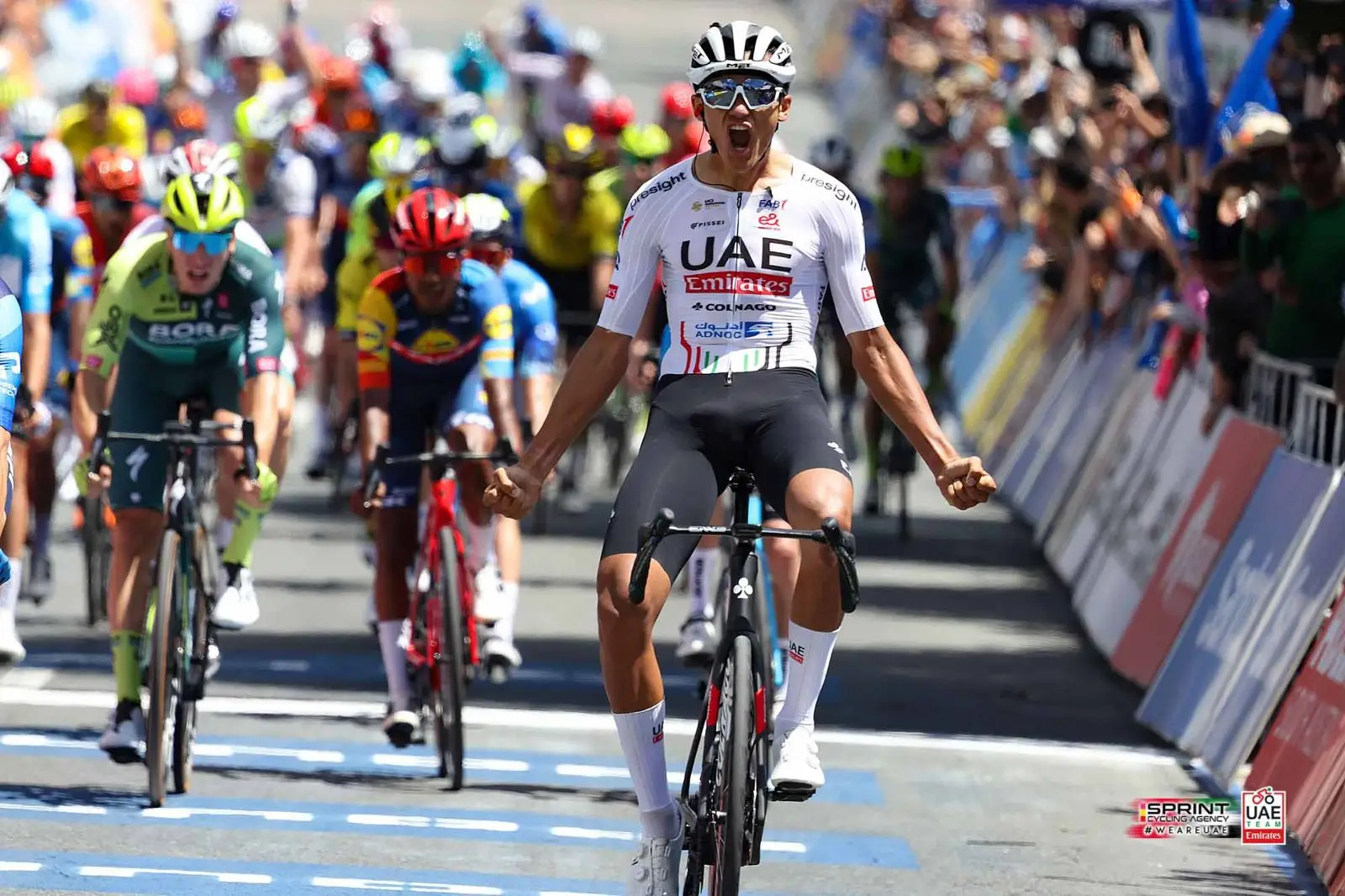 Isaac Del Toro celebrating on the Tour de France podium in the white jersey.