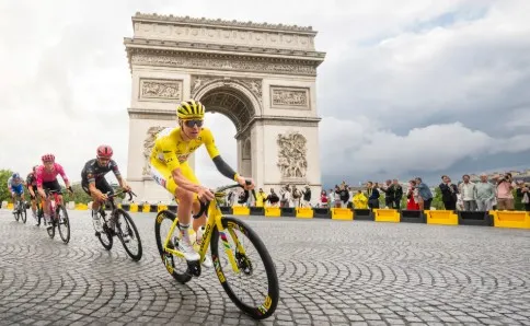 Peloton riding along the illuminated Champs-Élysées in Paris during the Tour de France finale.